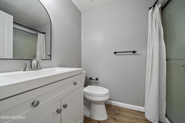 bathroom with hardwood / wood-style flooring, toilet, and vanity