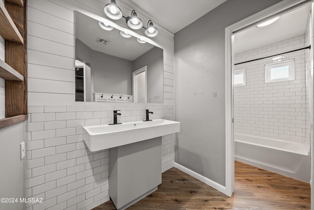 bathroom featuring hardwood / wood-style floors, backsplash, and tiled shower / bath