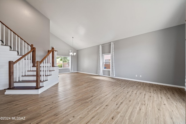 unfurnished living room with a notable chandelier, high vaulted ceiling, and light hardwood / wood-style flooring