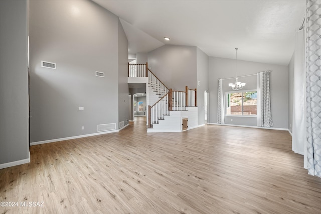 unfurnished living room with an inviting chandelier, light wood-type flooring, and high vaulted ceiling