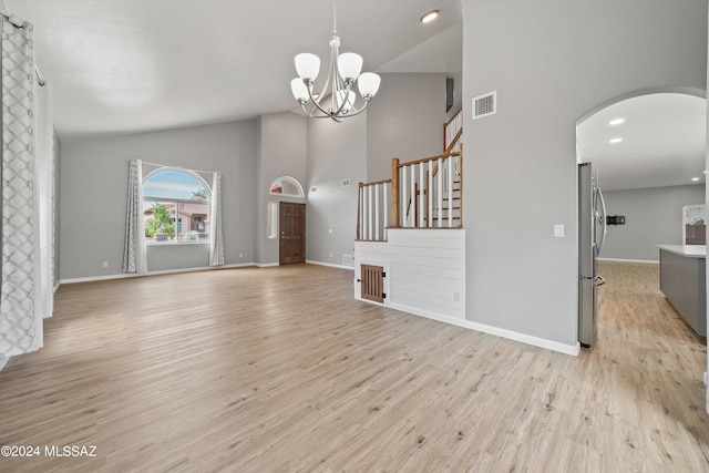 unfurnished living room featuring light hardwood / wood-style floors, vaulted ceiling, and a notable chandelier