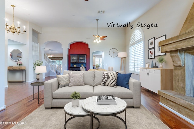 living room featuring a high ceiling, ceiling fan with notable chandelier, and hardwood / wood-style floors