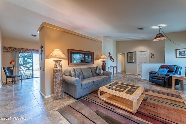 living area featuring lofted ceiling, visible vents, and baseboards