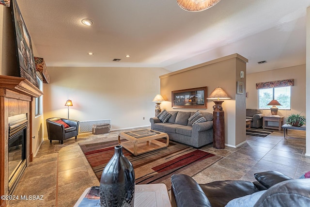 living area with baseboards, visible vents, a tiled fireplace, lofted ceiling, and recessed lighting