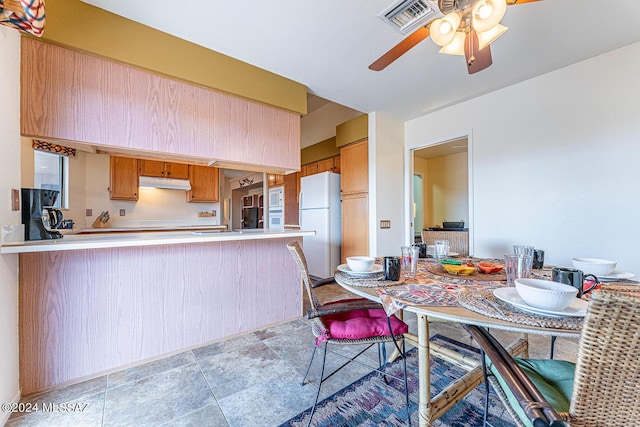 kitchen featuring under cabinet range hood, a peninsula, white appliances, visible vents, and light countertops