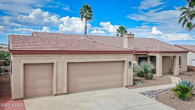 view of front of home with a tile roof, driveway, a chimney, and stucco siding