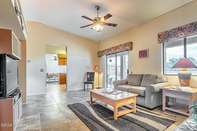 living room with vaulted ceiling, baseboards, a ceiling fan, and a healthy amount of sunlight