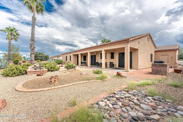 rear view of house with a patio area, an outdoor kitchen, and stucco siding