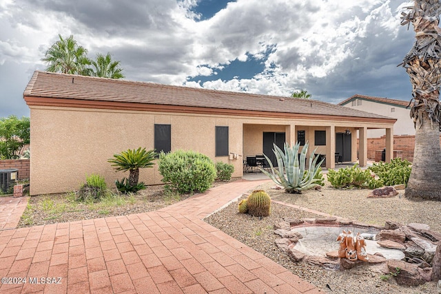 rear view of house with a patio area, fence, and stucco siding