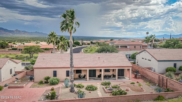 back of house with a mountain view, a patio, a fenced backyard, and a tiled roof