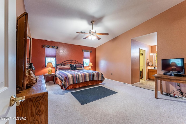 bedroom featuring carpet floors, lofted ceiling, a textured wall, a ceiling fan, and ensuite bath