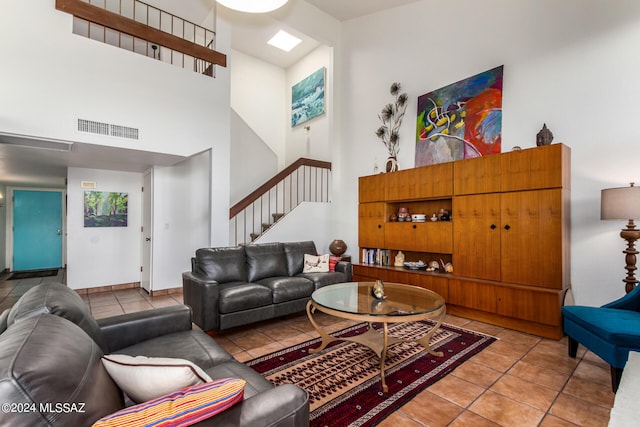 living room with a towering ceiling, tile patterned floors, and a skylight