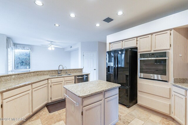 kitchen featuring ceiling fan, light stone counters, sink, a kitchen island, and appliances with stainless steel finishes