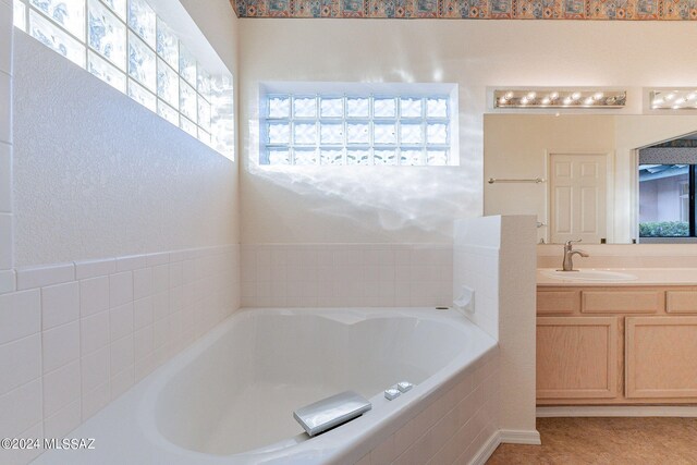 bathroom with tiled tub and vanity