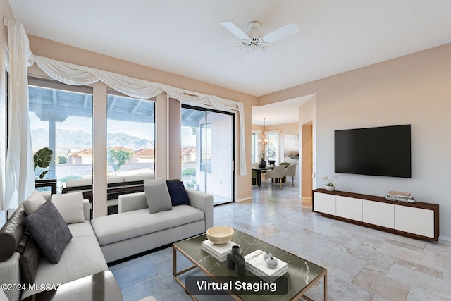 living room featuring ceiling fan with notable chandelier and a mountain view