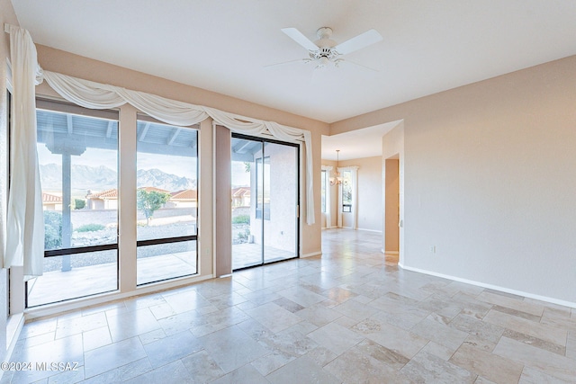 empty room with ceiling fan with notable chandelier and a mountain view