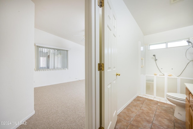 bathroom featuring a shower, vaulted ceiling, vanity, and toilet