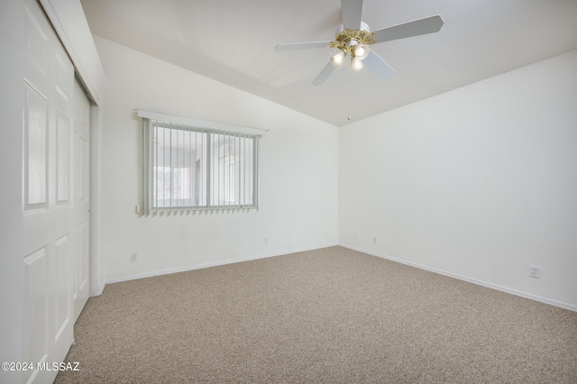 carpeted spare room featuring vaulted ceiling and ceiling fan