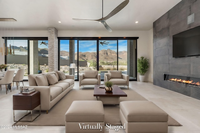 living room featuring ceiling fan, a fireplace, and light tile patterned floors