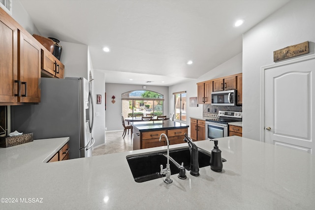 kitchen with vaulted ceiling, appliances with stainless steel finishes, sink, decorative backsplash, and kitchen peninsula