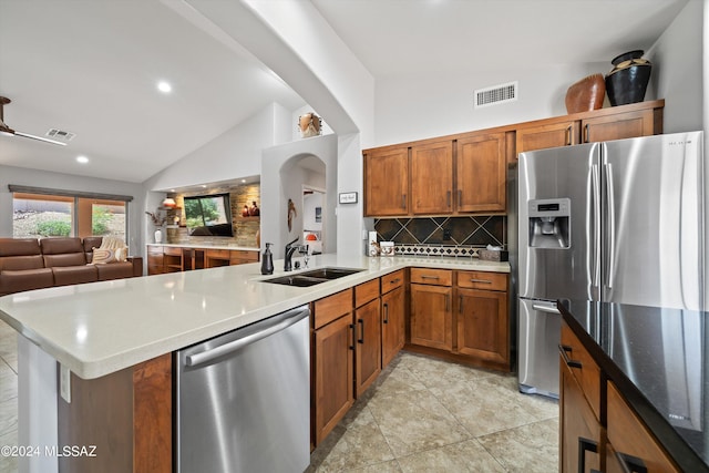 kitchen with lofted ceiling, appliances with stainless steel finishes, sink, and backsplash