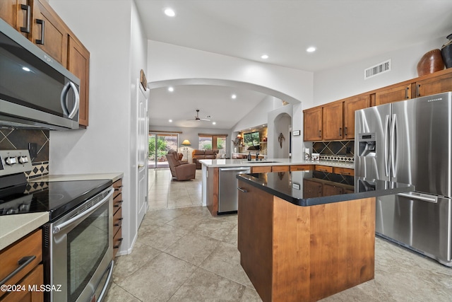 kitchen with a kitchen island, tasteful backsplash, appliances with stainless steel finishes, and kitchen peninsula