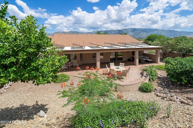 back of house featuring an outdoor living space, a mountain view, and a patio area