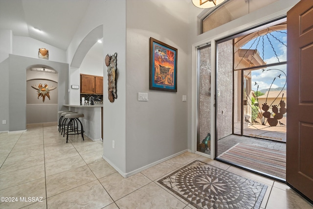 entrance foyer with light tile patterned flooring and vaulted ceiling