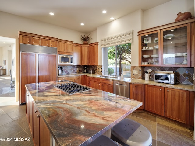 kitchen with built in appliances, backsplash, dark stone counters, and a kitchen island