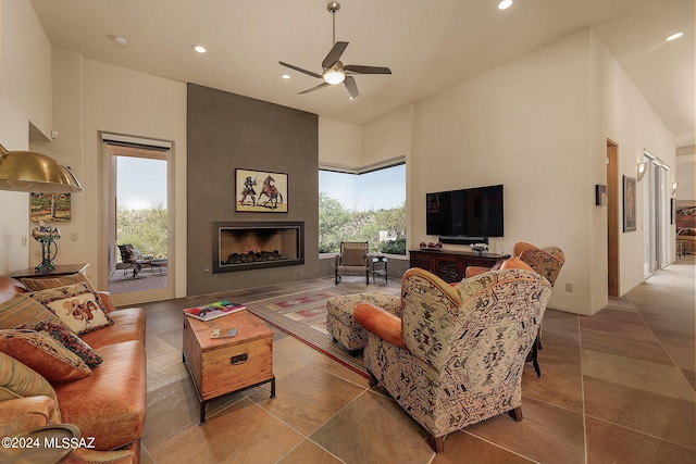 tiled living room featuring a high ceiling, a large fireplace, ceiling fan, and plenty of natural light