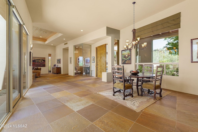 dining area with a raised ceiling and a notable chandelier