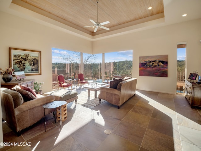 tiled living room with wood ceiling, a raised ceiling, and ceiling fan