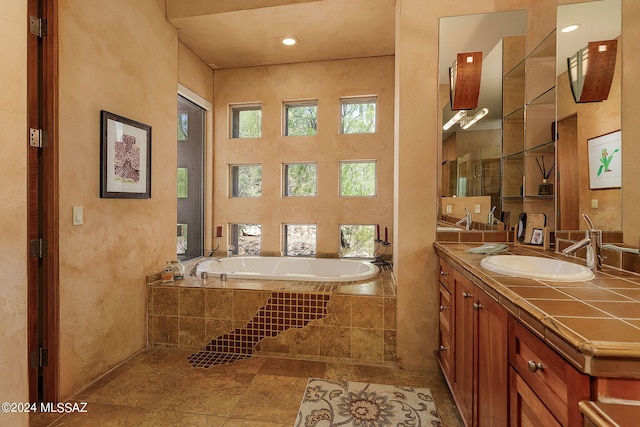 bathroom with vanity and tiled bath