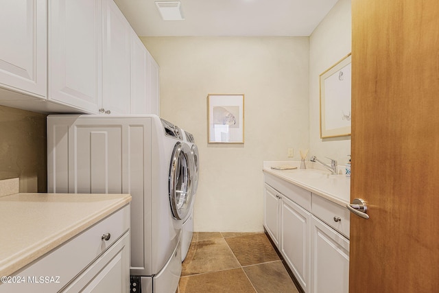 laundry room featuring washing machine and clothes dryer, cabinets, sink, and tile patterned flooring