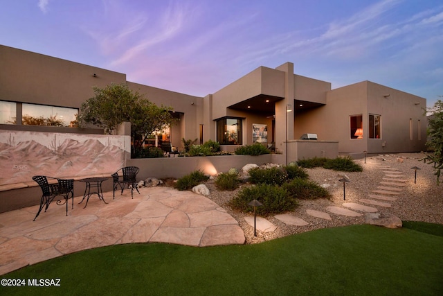 back house at dusk with a yard and a patio area