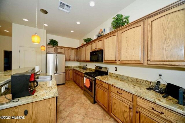 kitchen with light tile patterned flooring, light stone countertops, a kitchen island, and stainless steel appliances