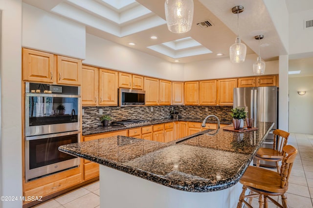 kitchen with tasteful backsplash, light tile patterned flooring, an island with sink, and stainless steel appliances