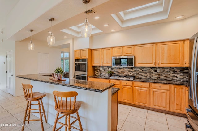 kitchen with appliances with stainless steel finishes, backsplash, a tray ceiling, and a center island