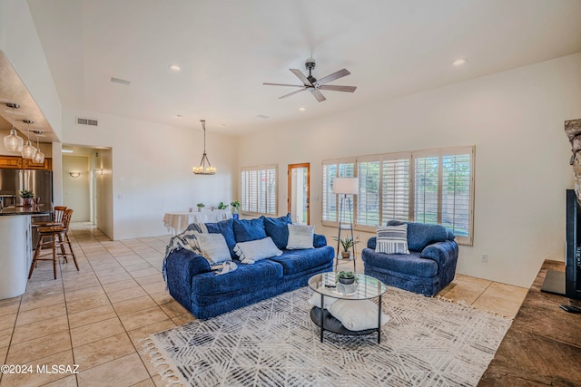 tiled living room with ceiling fan with notable chandelier