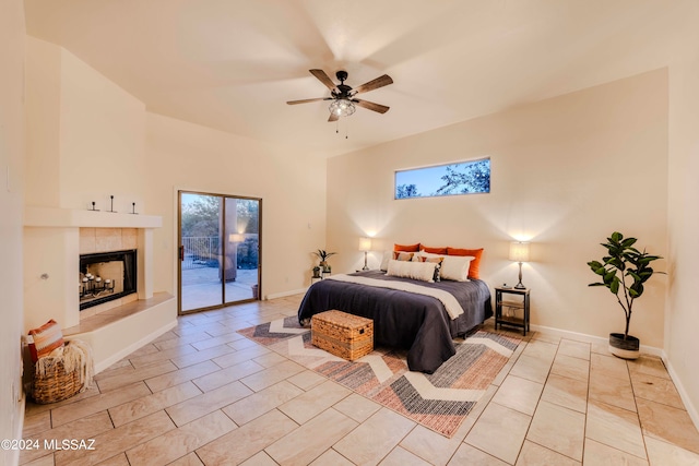 bedroom featuring a tiled fireplace, ceiling fan, light tile patterned flooring, and access to outside