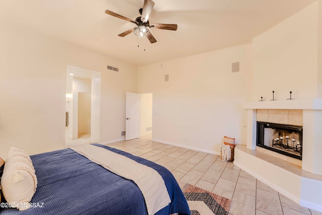 bedroom with a tile fireplace, light tile patterned floors, and ceiling fan