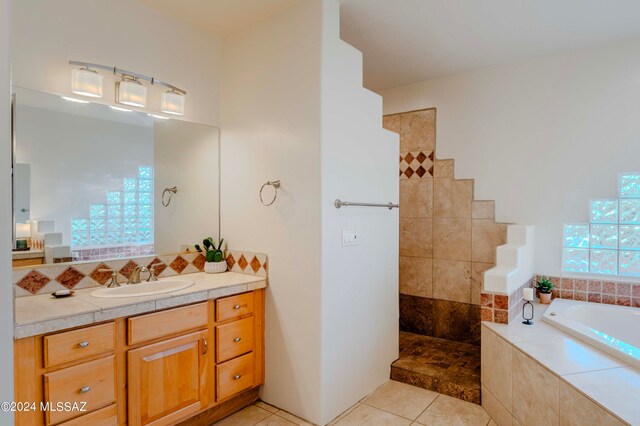 bathroom with tile patterned floors, tiled bath, and vanity