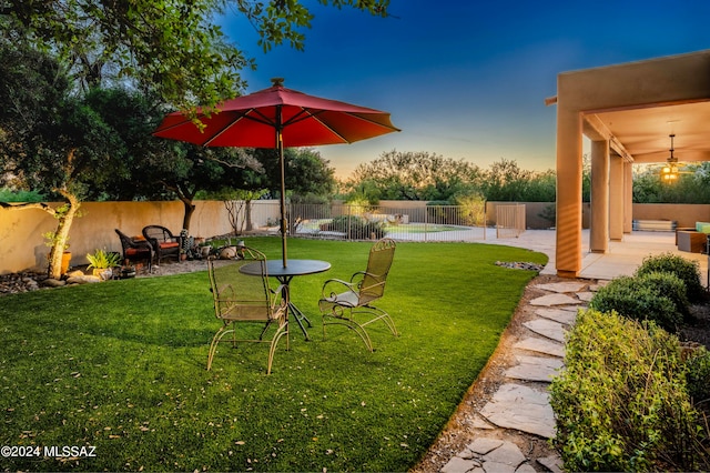 yard at dusk featuring a swimming pool and a patio area