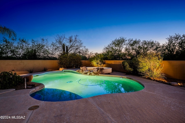 pool at dusk featuring a patio