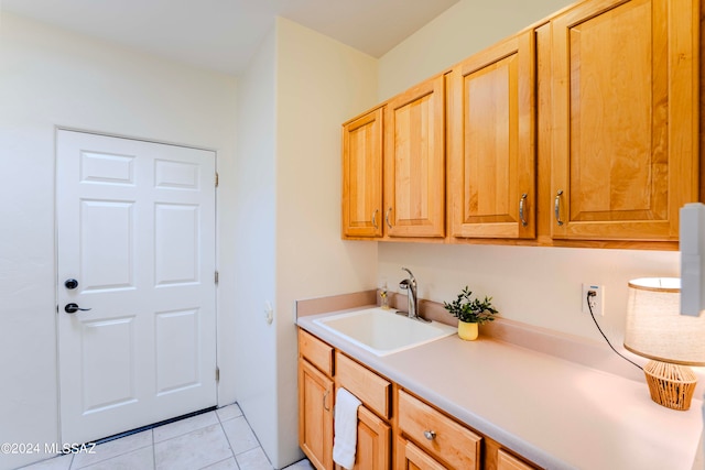 clothes washing area featuring cabinets, light tile patterned floors, and sink