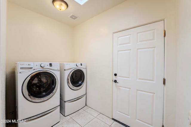 clothes washing area featuring washing machine and dryer and light tile patterned floors