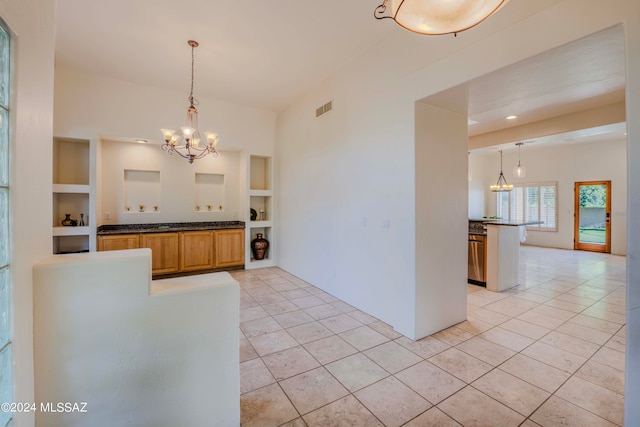 kitchen featuring kitchen peninsula, built in features, light tile patterned floors, and a chandelier