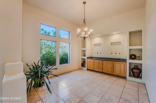 interior space featuring built in shelves, light tile patterned floors, hanging light fixtures, and an inviting chandelier