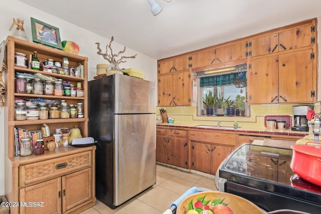 kitchen with sink, stainless steel refrigerator, range, and light tile patterned flooring