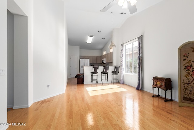 unfurnished living room with ceiling fan, high vaulted ceiling, and light wood-type flooring